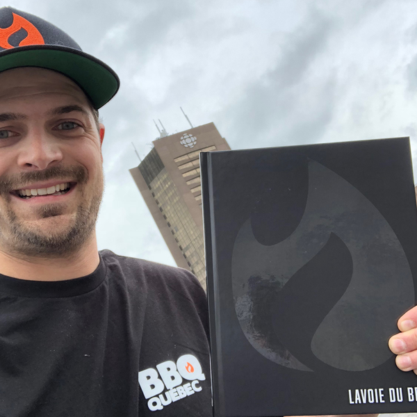 Max Lavoie pose devant l'édifice de Radio-Canada avec le livre Lavoie du BBQ